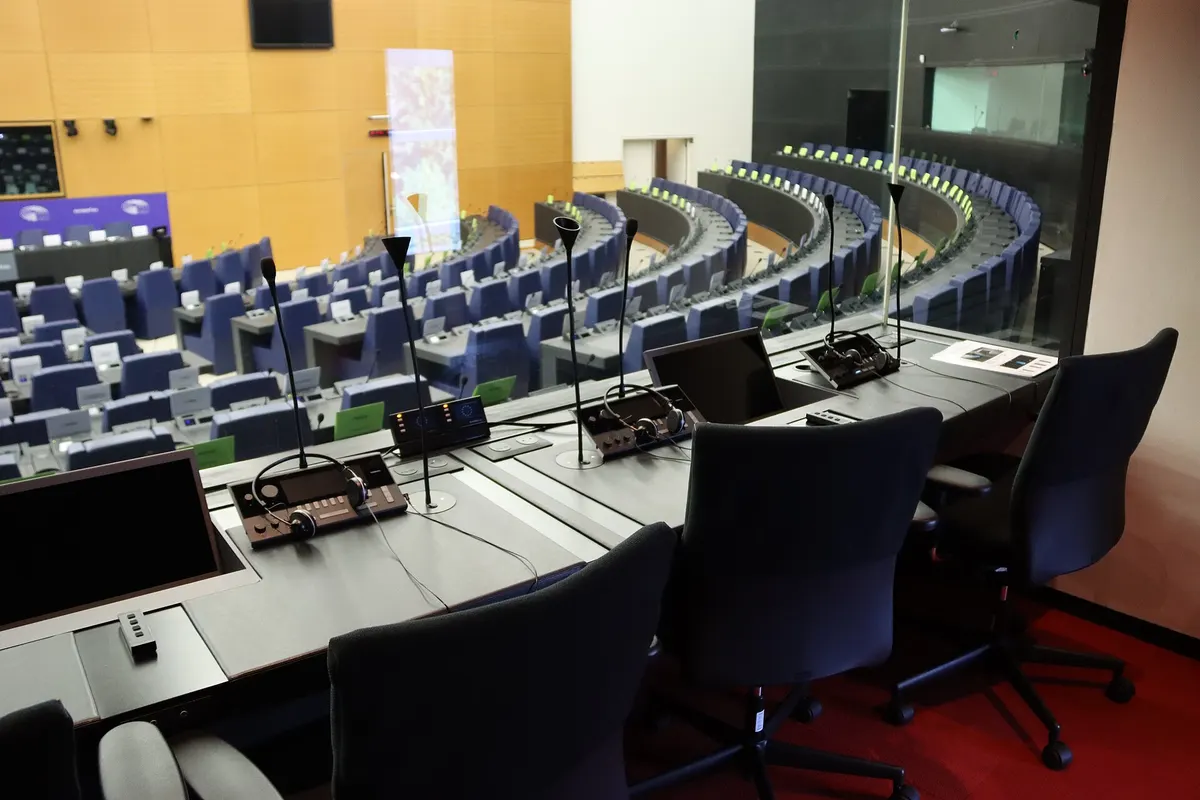 Cabina de interpretación con consolas, micrófonos y sillas frente al hemiciclo del Parlamento Europeo en Estrasburgo